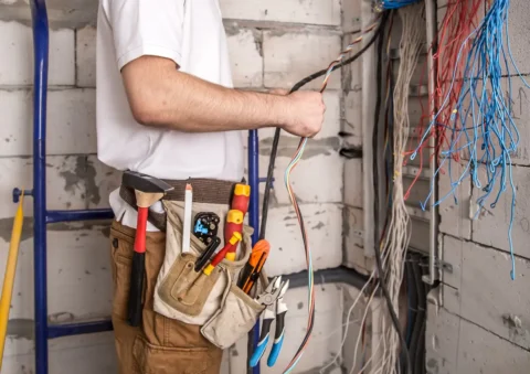 Elektrikár pracuje na elektroinštalácii v rozostavanej budove – inštalácia elektrických káblov počas výstavby elektrickej prípojky alebo rekonštrukcie rozvodov
